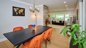 A dining area with a dark wooden table and orange upholstered chairs, a chandelier, and a world map on the wall.