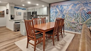 A modern kitchen with white cabinets, stainless steel appliances, and a dining area with wooden chairs and a table.