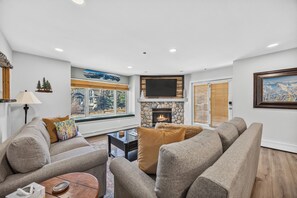 A living room with a fireplace, seating area, and large windows.