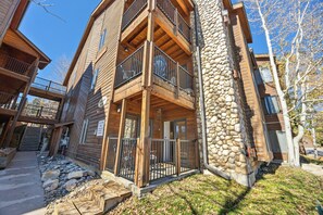 A multi-level wooden cabin with balconies, stone accents, and a clear sky.