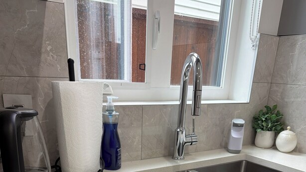 A modern kitchen with a double sink, a kettle, a paper towel dispenser, and a window. - YVR Stay - Vancouver YVR (Richmond)