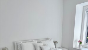 A minimalist bedroom with a white bed, nightstands, and a window with a view. - YVR Stay - Vancouver YVR (Richmond)