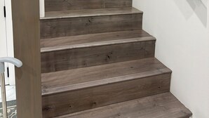 A wooden staircase with a handrail, leading to an upper floor. - YVR Stay - Vancouver YVR (Richmond)
