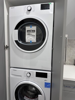 En stabling af vaskemaskine og tørretumbler med ENERGY STAR-mærke, digitalt display og kontrolpanel med forskellige indstillinger.
