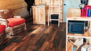 A wooden cabin interior with a sofa, a sink, a ladder, and a mounted cow head. - The Cabins at Bent Pine Ranch ~ Cabin #1 (Locust Grove)
