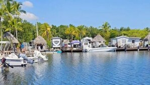 A water body with boats and thatched-roof huts. - 146 RV Vacation Rental n Key Largo Kampground, FL (Key Largo)