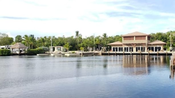 A waterfront property with a large building, dock, and surrounding greenery. - 146 RV Vacation Rental n Key Largo Kampground, FL (Key Largo)