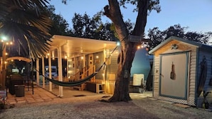 A cozy outdoor patio area with a hammock, a covered seating area, and a small shed. - 146 RV Vacation Rental n Key Largo Kampground, FL (Key Largo)