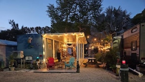 A cozy outdoor seating area with a covered structure, surrounded by potted plants and a gravel ground. - 146 RV Vacation Rental n Key Largo Kampground, FL (Key Largo)