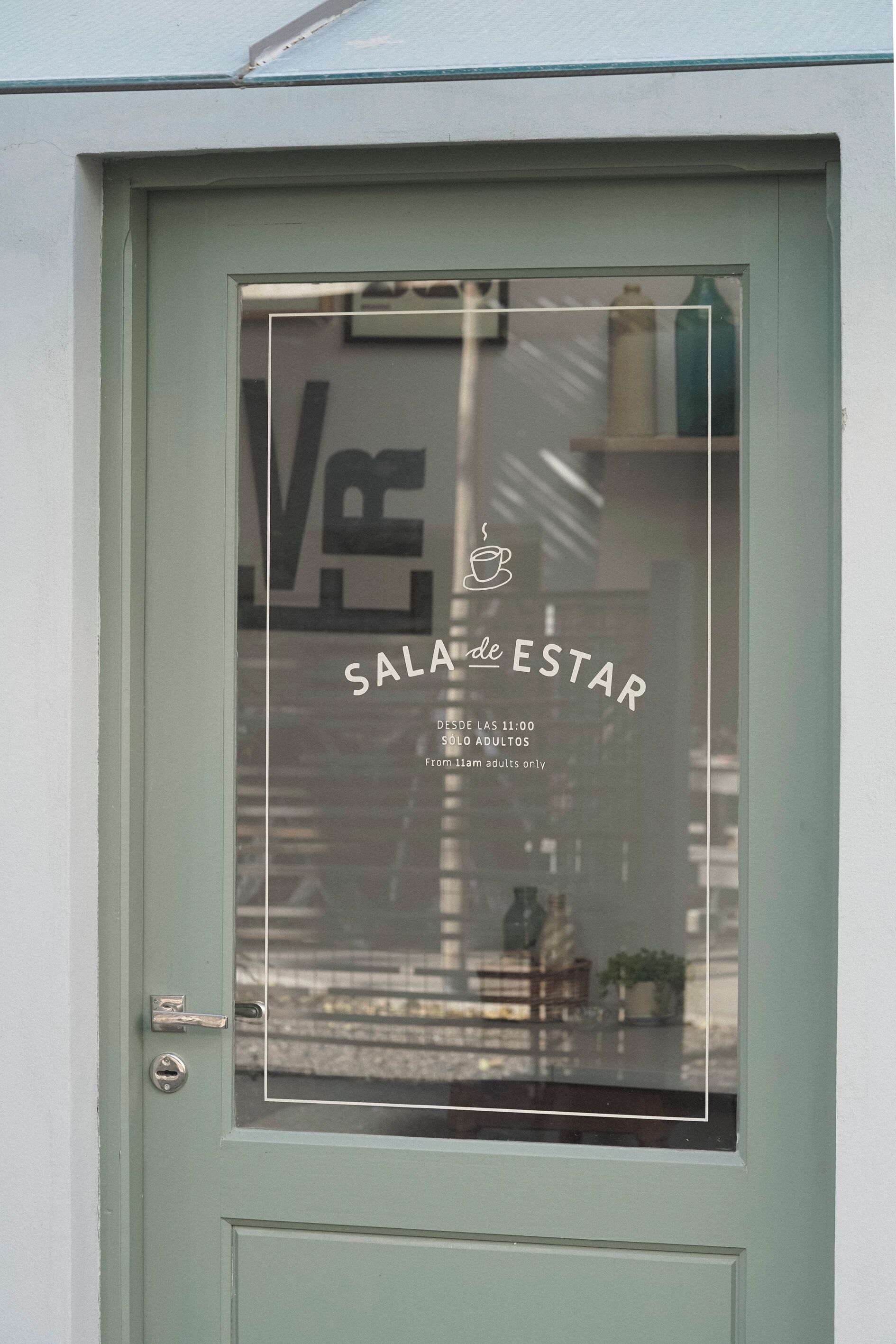 A door with a window displaying 'Sala de Estar' and 'From 11:00 to 23:00 adults only' text.