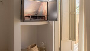 A room with a TV mounted on the wall, a woven basket, and a glass jar on the floor. - El Poblado (Puerto Madryn)