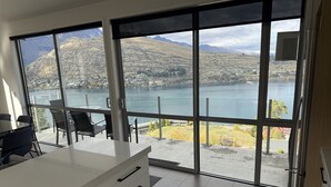 Eine moderne Küche mit großen Fenstern, die auf einen See und Berge blicken.