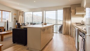 Une cuisine moderne dotée d’un grand îlot central, d’un coin repas et offrant une vue sur un paysage montagneux.