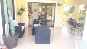 An indoor patio area with wicker furniture, potted plants, and a view of the outdoor space. - DREAM VACATION HOME (Sosúa)