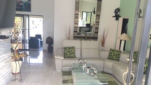 A modern living room with a white sofa, glass coffee table, and decorative items. - DREAM VACATION HOME (Sosúa)