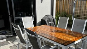 Une terrasse extérieure avec une table rectangulaire en bois et six chaises.
