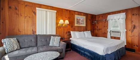 Spacious unit with a king bed, cozy sitting area, and classic wood-paneled charm - perfect for a restful stay.