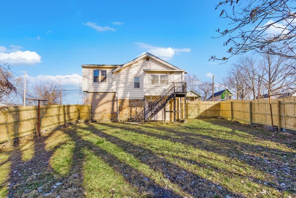 A two-story house with a wooden deck and a staircase leading to the second floor.