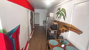 Un pasillo estrecho con una zona de comedor que incluye una mesa, sillas, un refrigerador y un microondas.