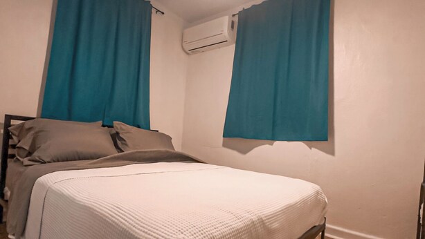 Un dormitorio con cama, ventilador de techo y unidad de aire acondicionado.