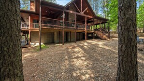 A cabin with a covered deck, a staircase, and a gravel ground.