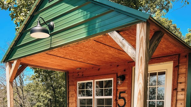 A wooden cabin with a porch, two chairs, and a door marked with the number 5.