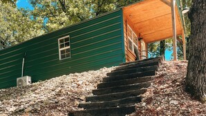A set of wooden steps leading up to a green building with a covered porch.