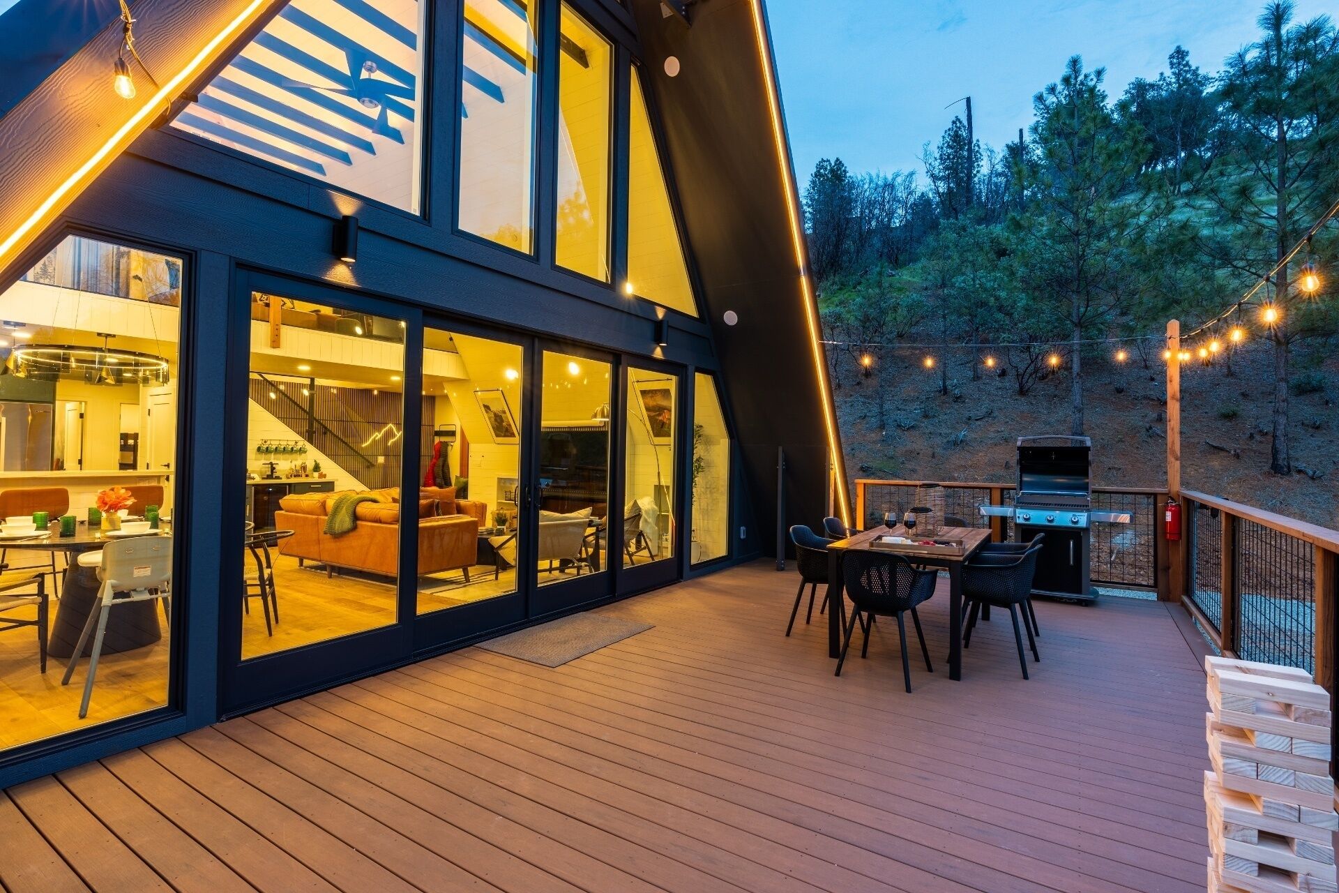 Una casa moderna con terraza, comedor y cocina visibles a través de amplios ventanales.