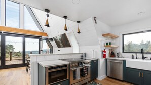 A modern kitchen with a large island, stainless steel appliances, and a view of the outdoors.