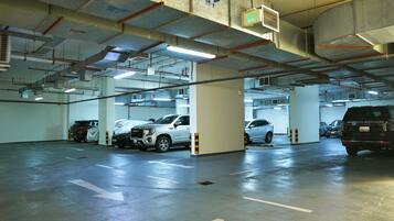 An underground parking garage with multiple levels, concrete pillars, and directional arrows on the floor.