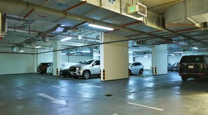 An underground parking garage with multiple levels, concrete pillars, and directional arrows on the floor.