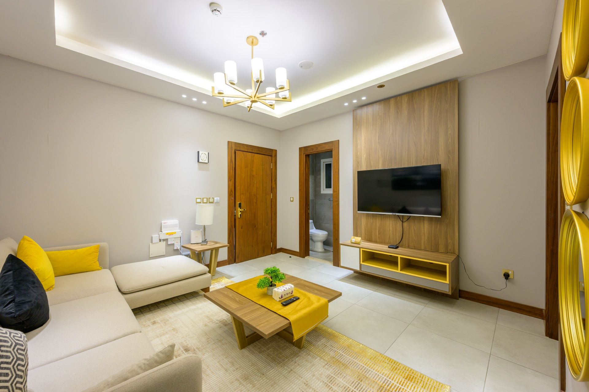 A modern living room with a sofa, coffee table, TV, and a wooden cabinet.