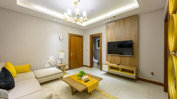 A modern living room with a sofa, coffee table, TV, and a wooden cabinet.