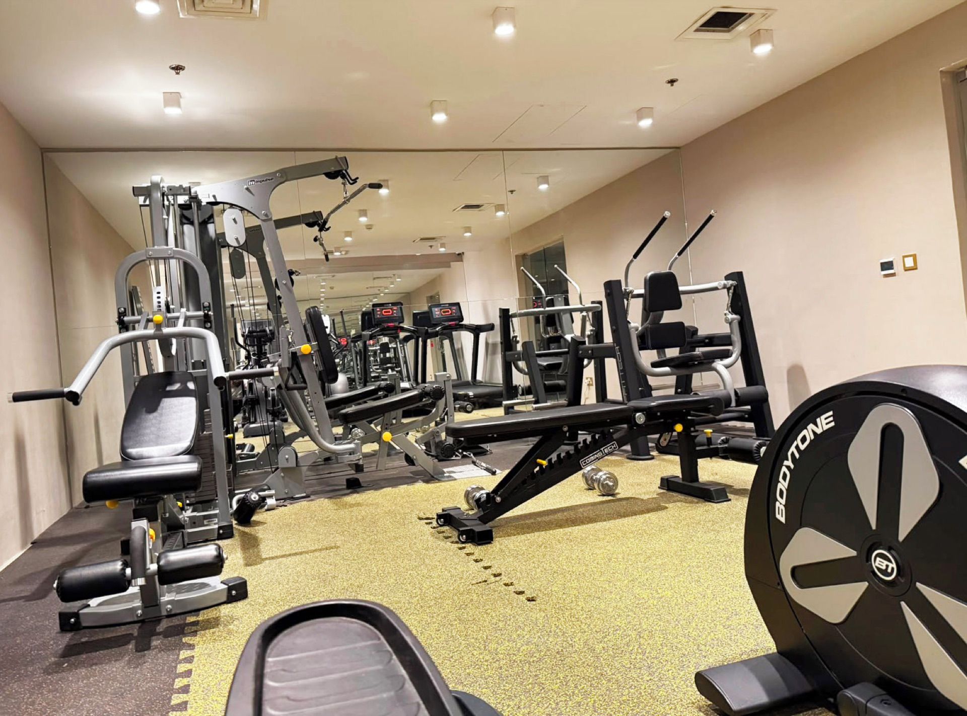A gym with various exercise machines, a weight bench, and a cardio machine.