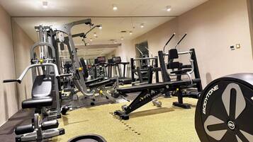 A gym with various exercise machines, a weight bench, and a cardio machine.