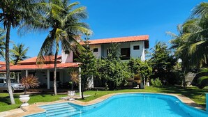Una piscina de borde curvo, rodeada por un césped cuidado y palmeras.