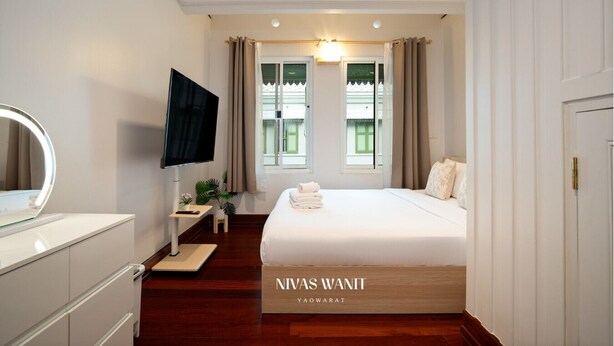Ein Hotelzimmer mit Bett, Fernseher, Schreibtisch und einem Fenster mit Vorhängen.