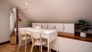Eine kleine Küche mit einer weißen Arbeitsplatte, Holzstühlen und Schränken.