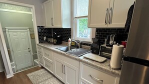 Una cucina moderna con mobili bianchi, un frigorifero in acciaio inossidabile e un rivestimento a contrasto bianco e nero.