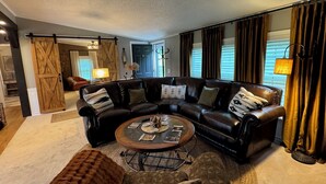 A modern living room with a sectional sofa, a coffee table, and a sliding barn door.
