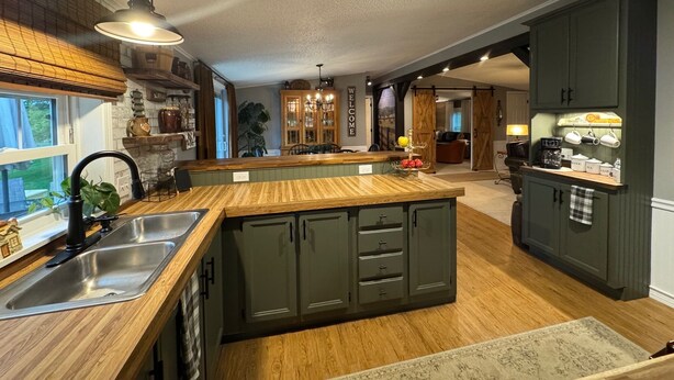 A modern kitchen with a central island, dark cabinetry, and a farmhouse-style aesthetic.