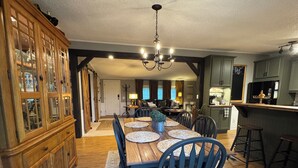 A spacious dining area with a wooden table, black chairs, and a chandelier.