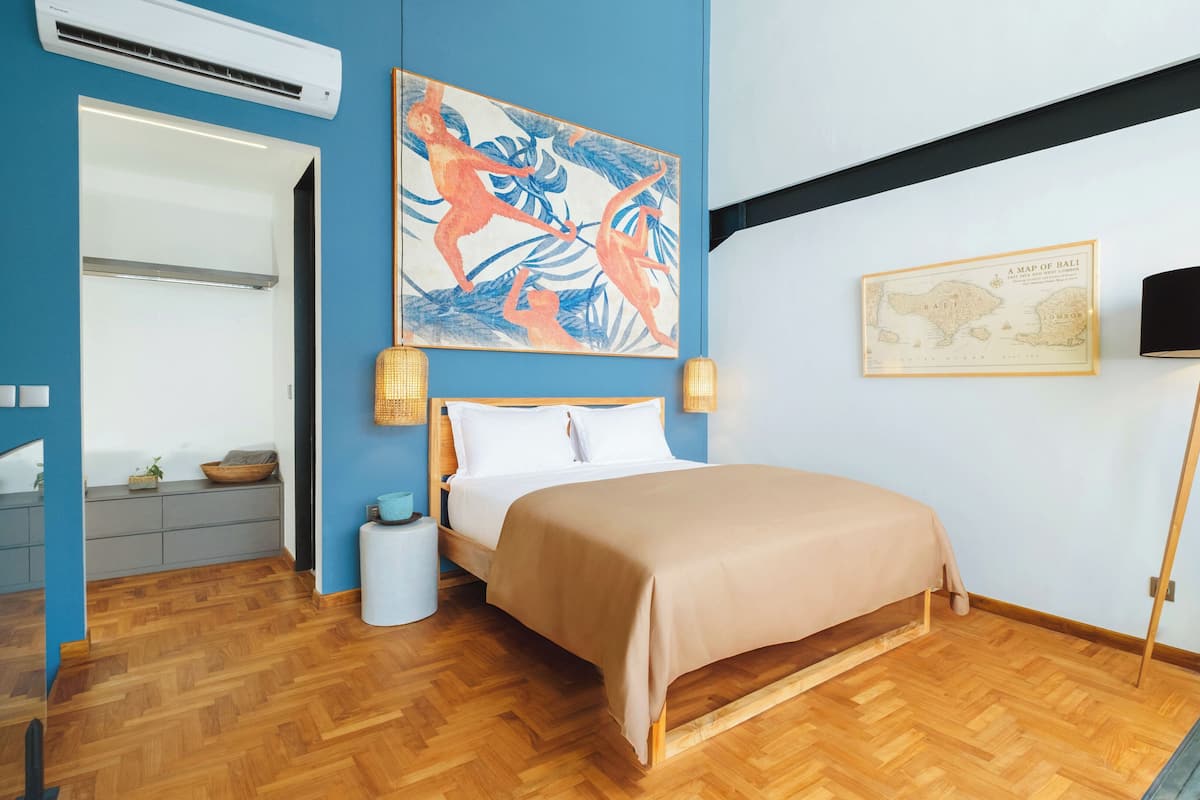 A bedroom with a bed, a map of Bali, a lamp, and a blue wall.