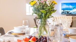 A dining table set with plates, bowls, cutlery, glasses, and a vase with flowers.