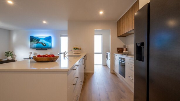 A modern kitchen with a central island, built-in appliances, and a large flat-screen TV.