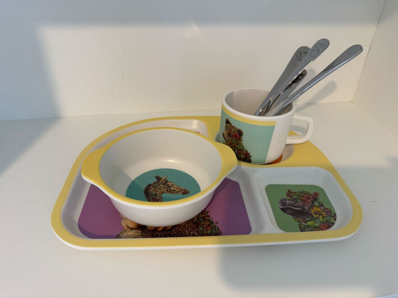 Ein Tablett mit einer weißen Schüssel, einer Tasse und einem Löffelset.