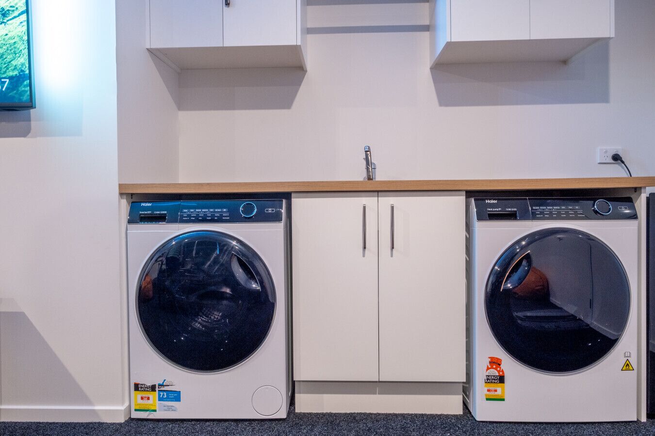 Een wasruimte met twee voorladers, een houten aanrechtblad en witte kastjes.