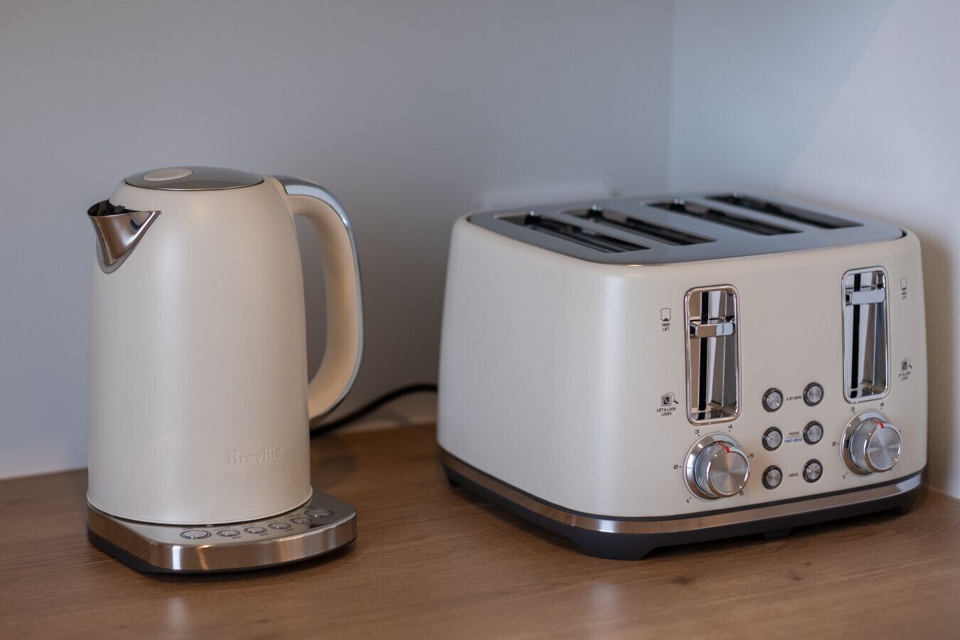 Een elektrische waterkoker en een broodrooster van Breville op een houten oppervlak.