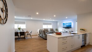 A modern kitchen with a central island, a dining area with a table and chairs, and a living area with a sofa.