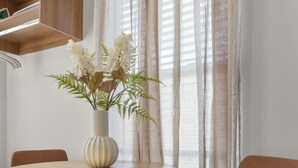 Un'area pranzo moderna con un tavolo rotondo in legno, un vaso con fiori e una sedia marrone.